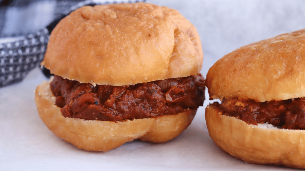 Two South African Vetkoek filled with curried meat on white paper