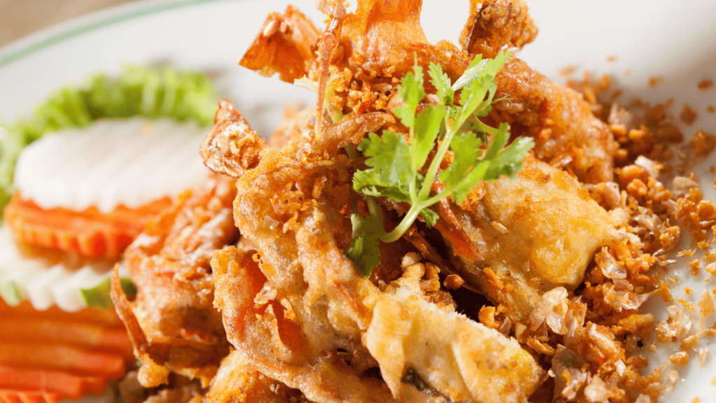 Fried soft shelled crab on a plate with a piece of parsley on top